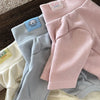 A stack of pink and gray soft stretch dog pajamas for small and medium pets with brand tags.