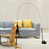 An orange cat is interacting with a long, black suction cup wand toy in a modern living room setting.