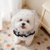 Un perro blanco vistiendo un collar de malla transparente con estrellas doradas y un borde de volantes negros.