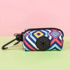 A colorful patterned pouch designed to hold dog waste, featuring a black clip and a circular opening.