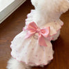 A white pet dress with pink trim and a pink bow featuring a silver leash ring