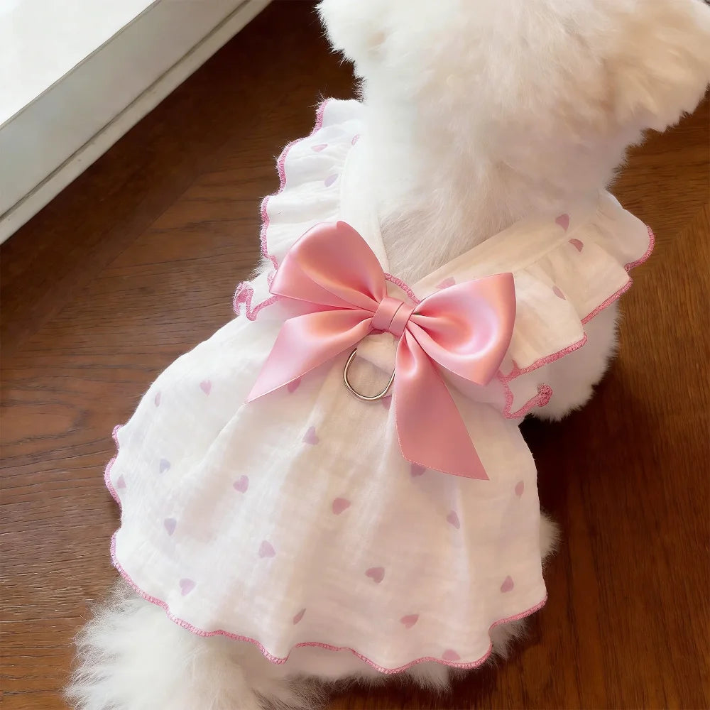 A white pet dress with pink trim and a pink bow featuring a silver leash ring