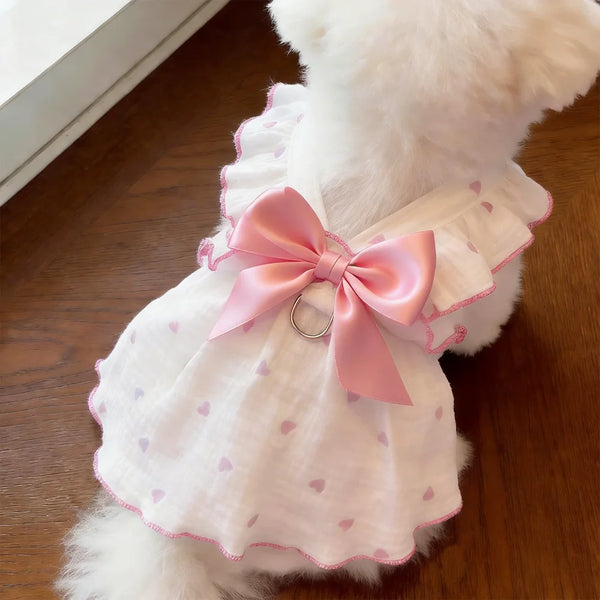 A white pet dress with pink trim and a pink bow featuring a silver leash ring