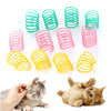 A collection of colorful spiral spring toys for cats and ferrets next to a kitten.