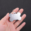 Silver bone-shaped dog ID tag held in a person's hand against a dark background