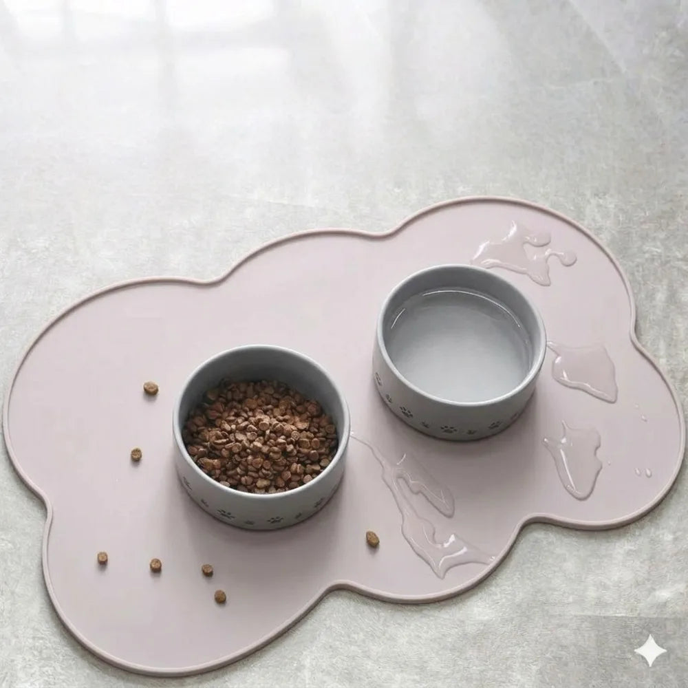 A pink non-slip pet mat features two small ceramic bowls on a light gray surface.