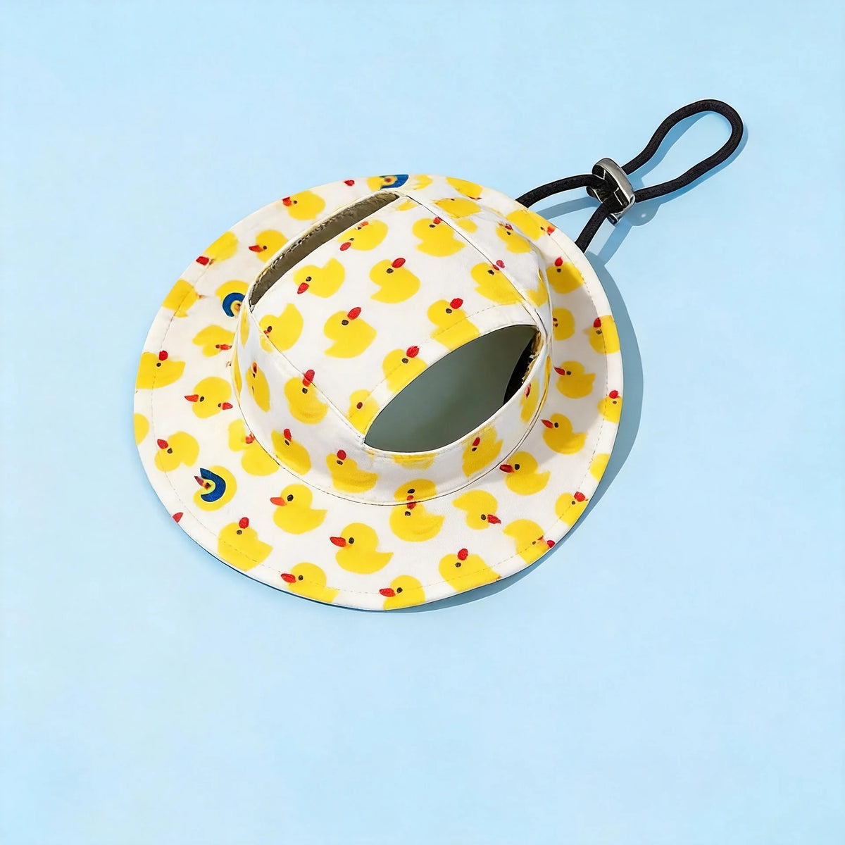 A yellow and white cartoon duck print bucket hat with a black strap against a light blue background.