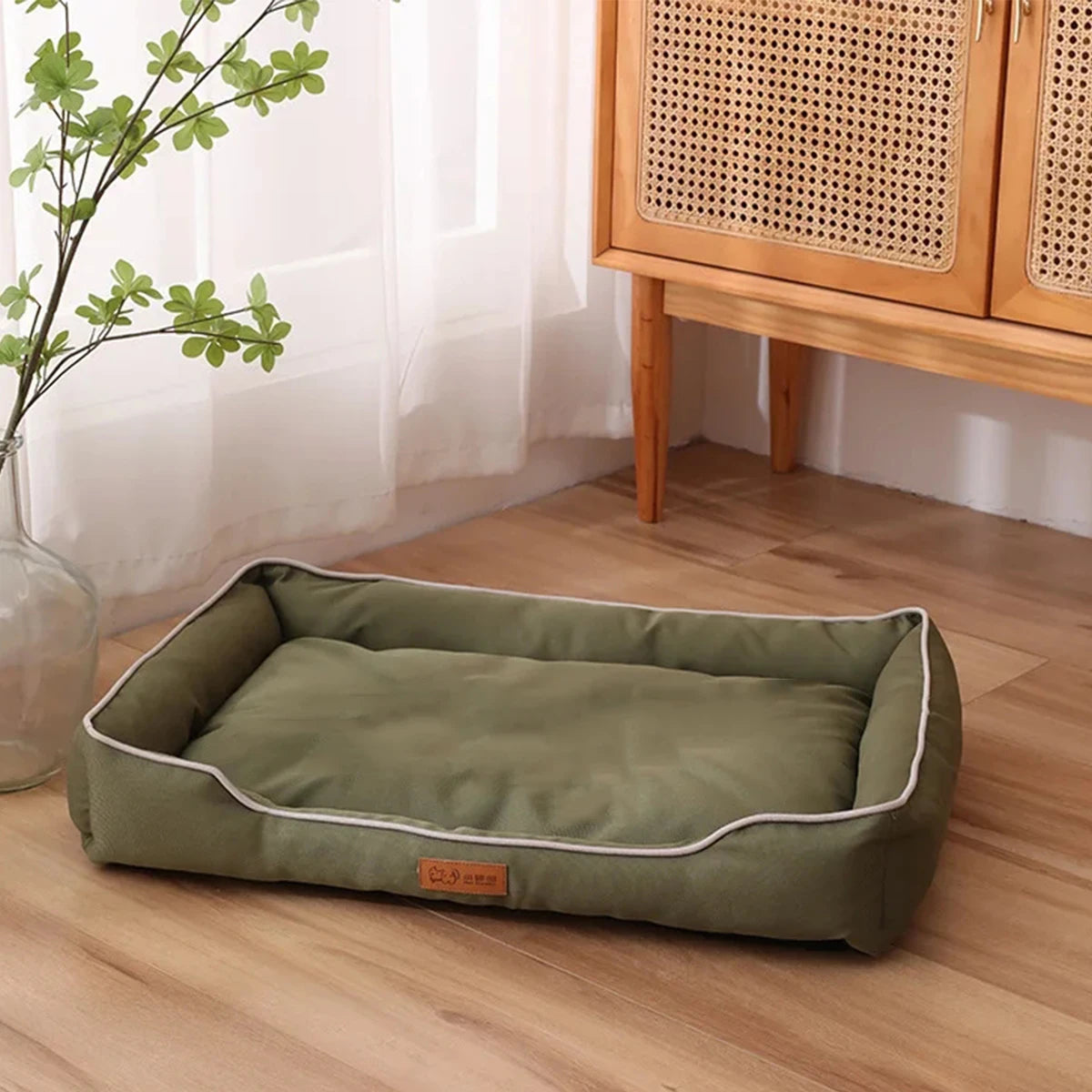 A rectangular olive green orthopedic dog bed with a removable cover resting on a wooden floor.