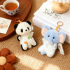 A pair of soft, white and blue cartoon animal bean bag plush toys resting on a light brown textured surface.