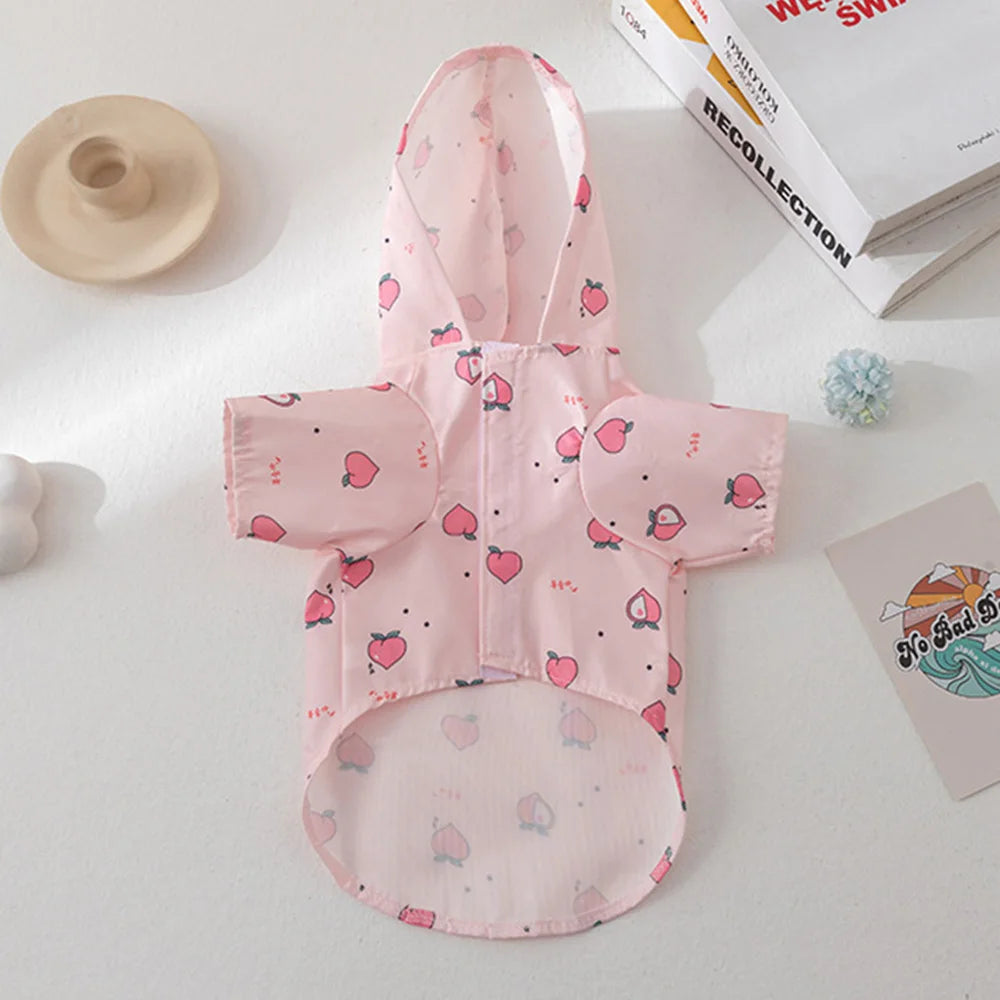 Pink cartoon printed dog raincoat for small breeds displayed on a white surface.
