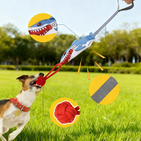 A dog is playing with an interactive tug of war rope toy, which features a dragon head design and is being pulled by a person