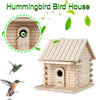 A wooden hummingbird bird house with a perch shown next to a small bird and leaves.