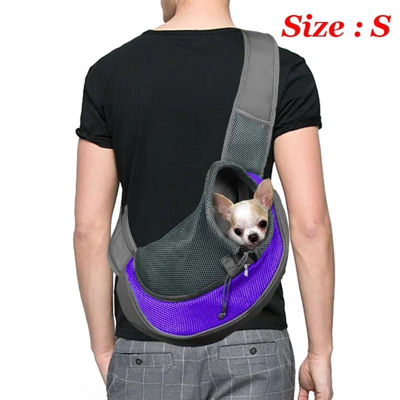 A person is wearing a gray breathable dog sling carrier with a small dog inside, against a white background.