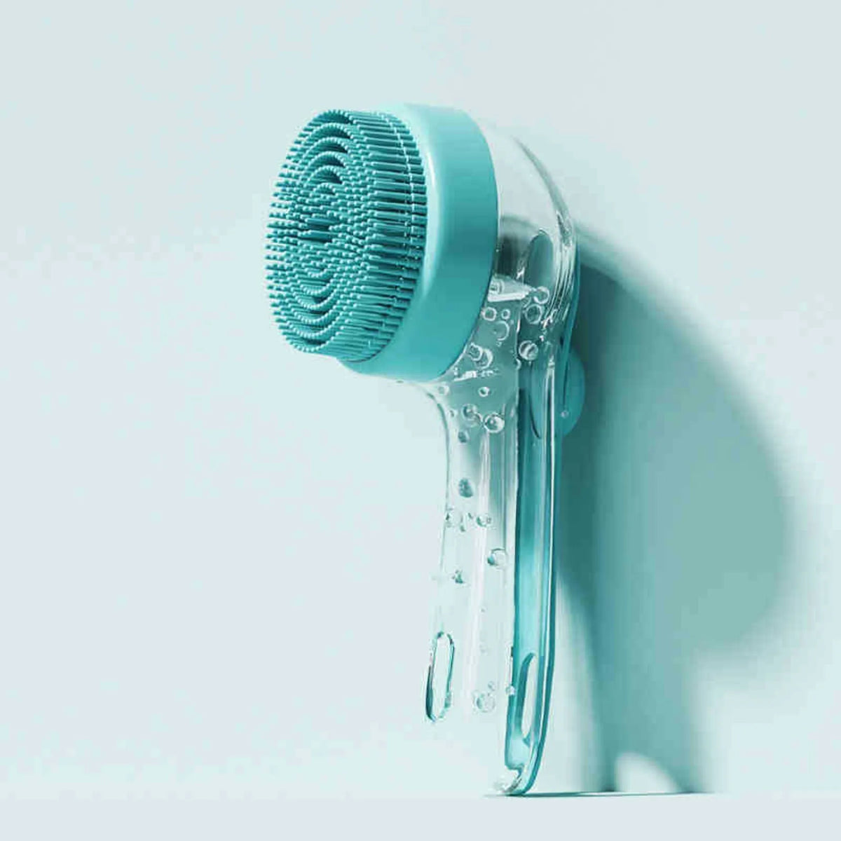 Brosse de bain en silicone bleu clair pour animaux avec des poils verts texturés.