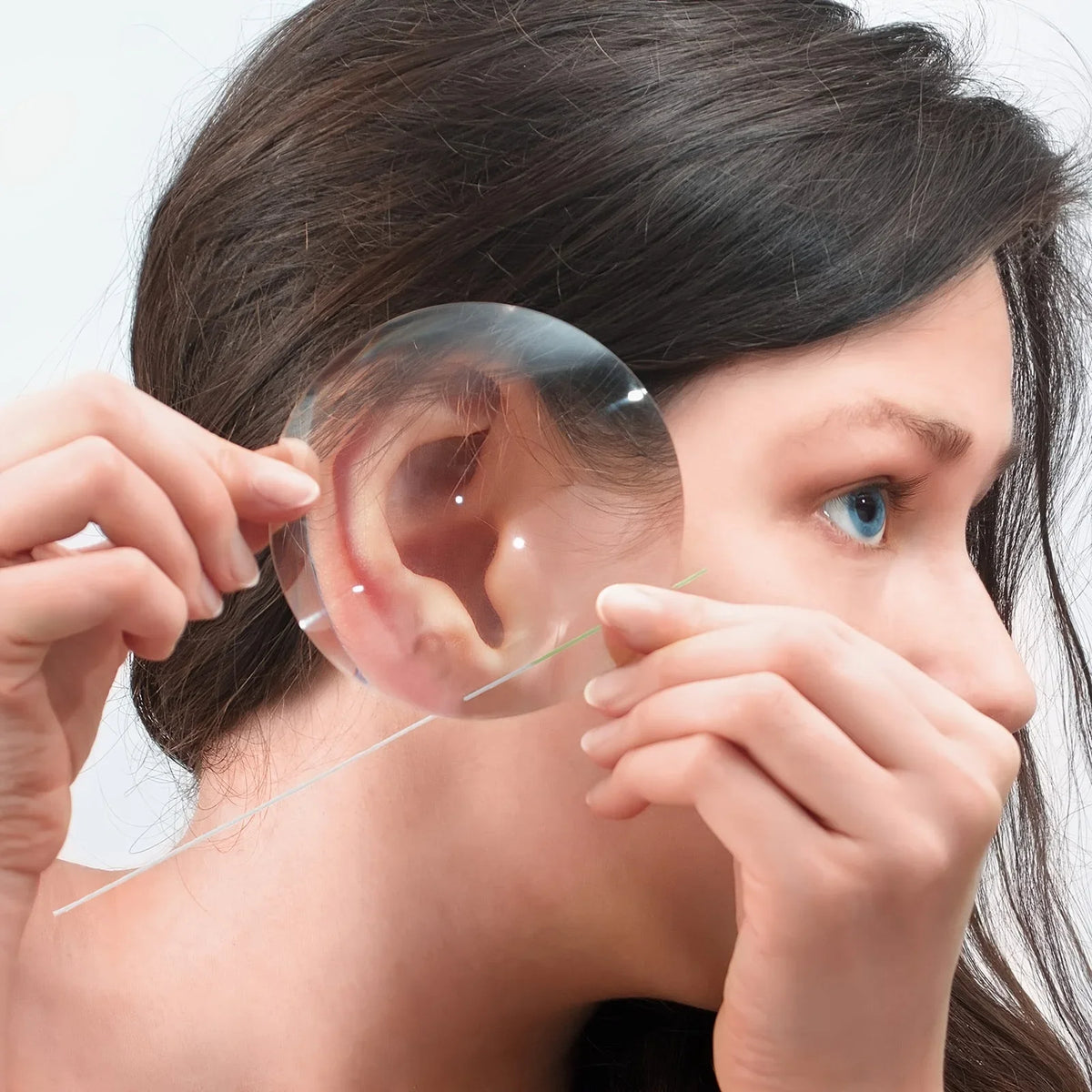 A woman is using a disposable ear cleaning tool to examine her ear.