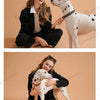 A woman is holding a white dog with black spots, posing outdoors.