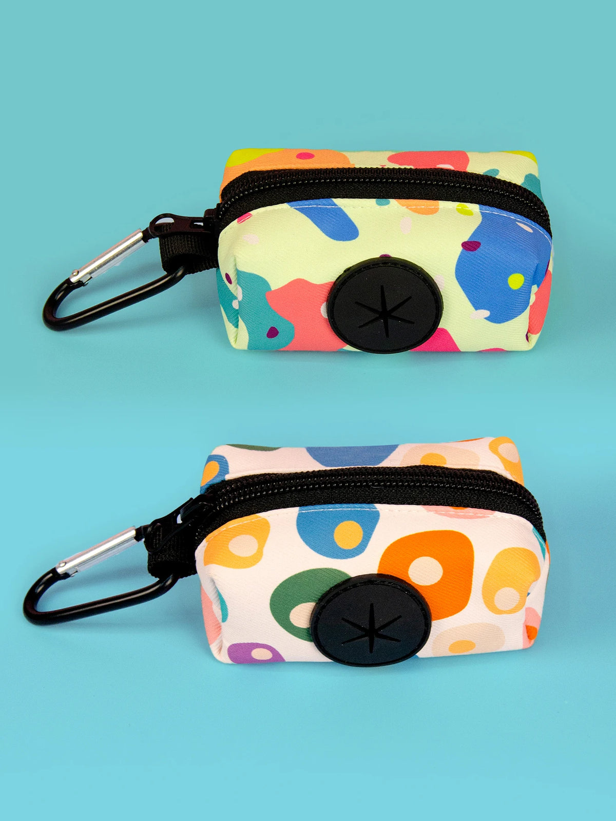 A colorful, patterned poop bag holder with a black strap and clip is shown against a light blue background.
