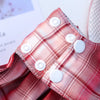 Close-up of a red plaid pet dress-up harness featuring white buttons.