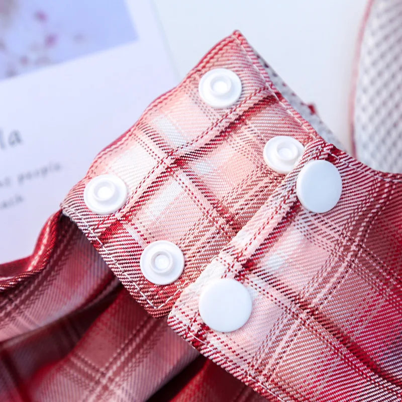 Close-up of a red plaid pet dress-up harness featuring white buttons.