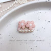 Pink bow hair accessory with pearl rhinestone accents displayed on a white plate.