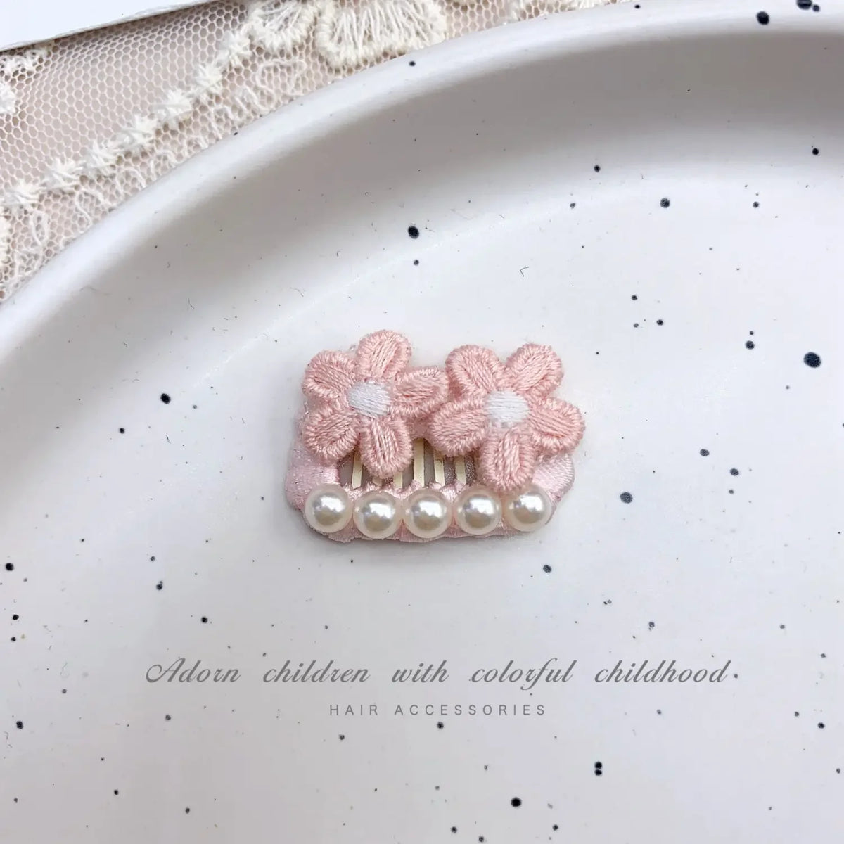Pink bow hair accessory with pearl rhinestone accents displayed on a white plate.