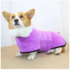 A small dog wearing a purple quick-dry microfiber robe on a beige surface.