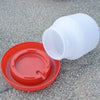 White plastic automatic poultry feeder and waterer with an orange lid placed on a gray surface.