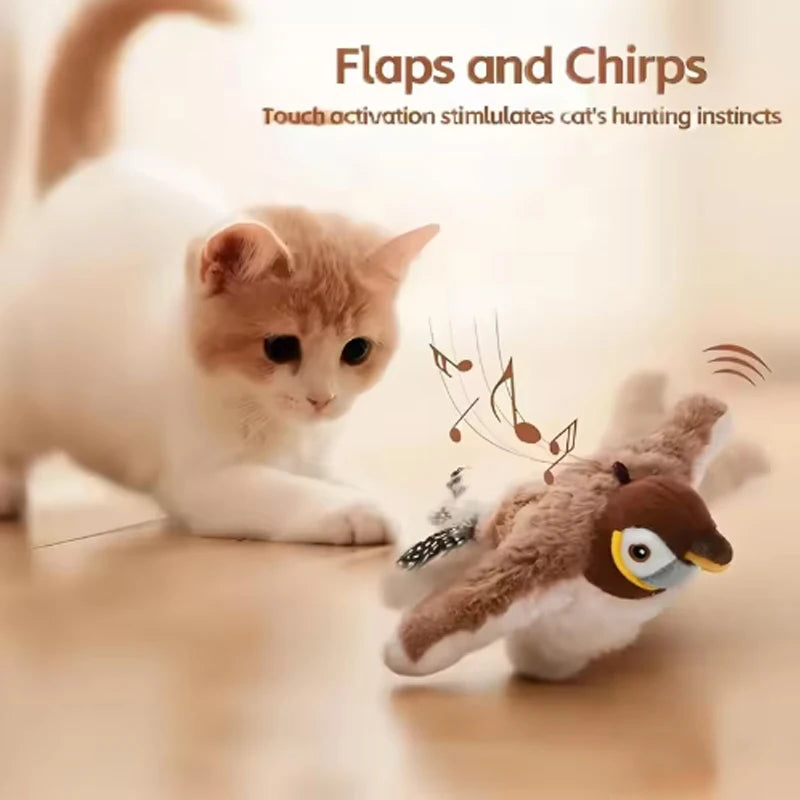 A small, fluffy cat toy resembling a bird with flapping wings and chirping features is shown on a wooden surface.