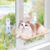 A fluffy white and ginger cat is relaxing on a suction cup hammock designed for windowsills.