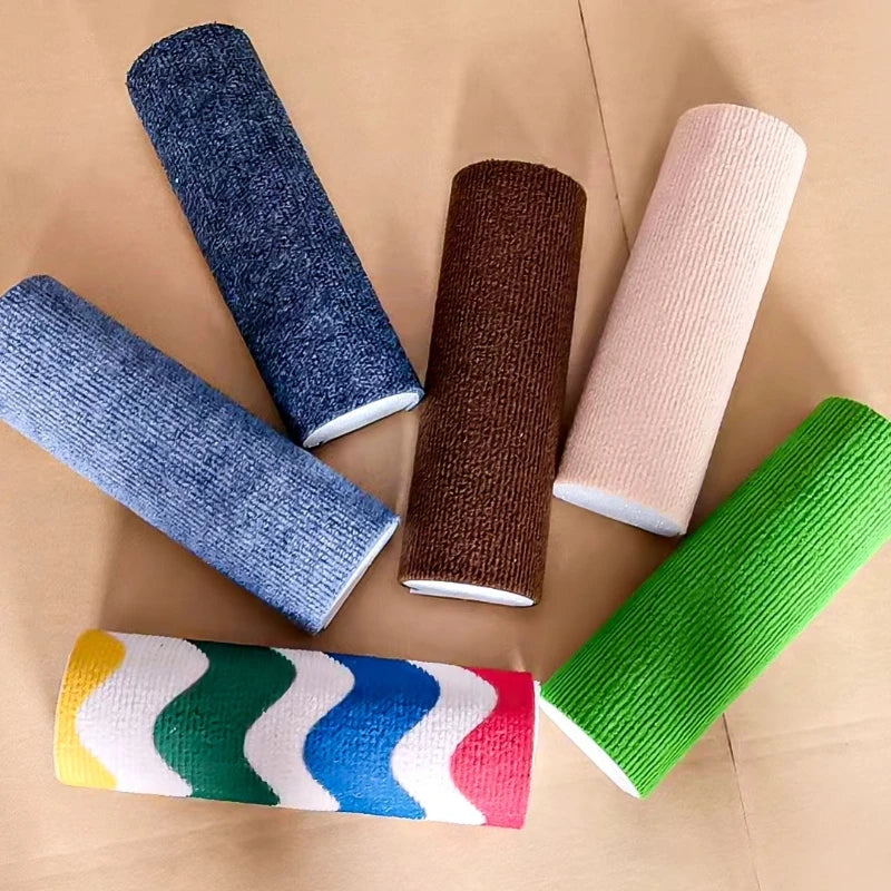 A collection of rolled cat scratching boards in various colors including blue, brown, pink, and green on brown paper.