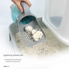 A hand is using a gray integrated cat litter scoop to pick up a ball of litter from a litter box.