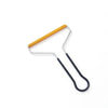 A manual lint remover brush with a metal frame and a yellow bristled stick.