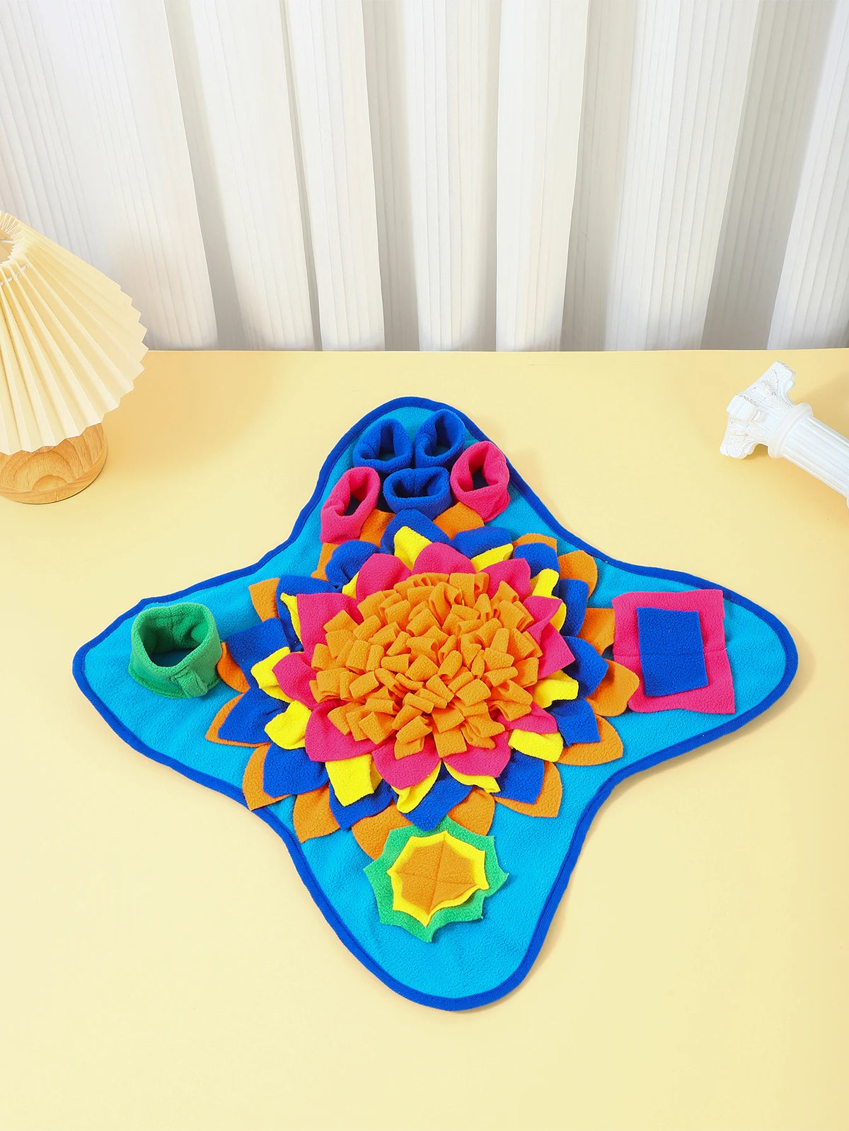 A bright blue snuffle mat with colorful fabric pieces for slow feeding puzzle toy.