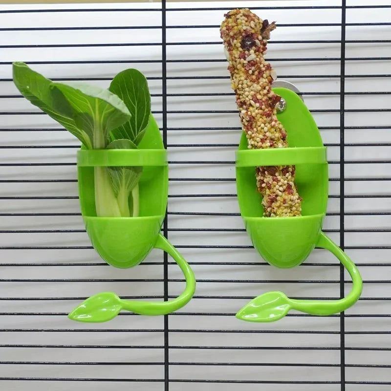 A green feeding stand holds a piece of bird cuttlebone for parrots against a black wire grid background.