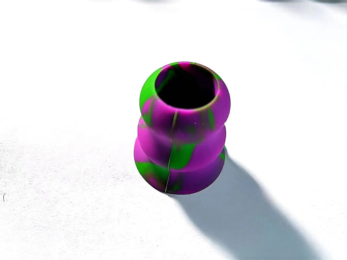 A close-up view of a silicone bat grip knob with a vibrant purple and green marbled pattern.