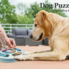 Ein goldener Hund interagiert mit einem blauen Puzzle-Futterspielzeug, das von einer Person gehalten wird.