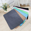 A stack of colorful, hexagonal reusable washable pet training mats on a light wooden floor.