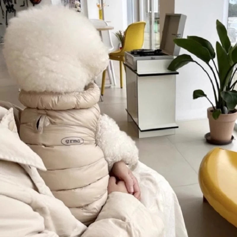 Beige Daunenjacke für Hund oder Katze liegt auf weißer Oberfläche.