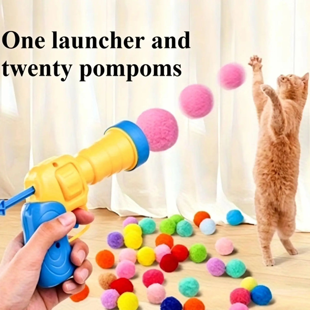 Eine Hand hält einen gelben Launcher mit zwanzig bunten Pompons, mit einer Katze im Hintergrund.