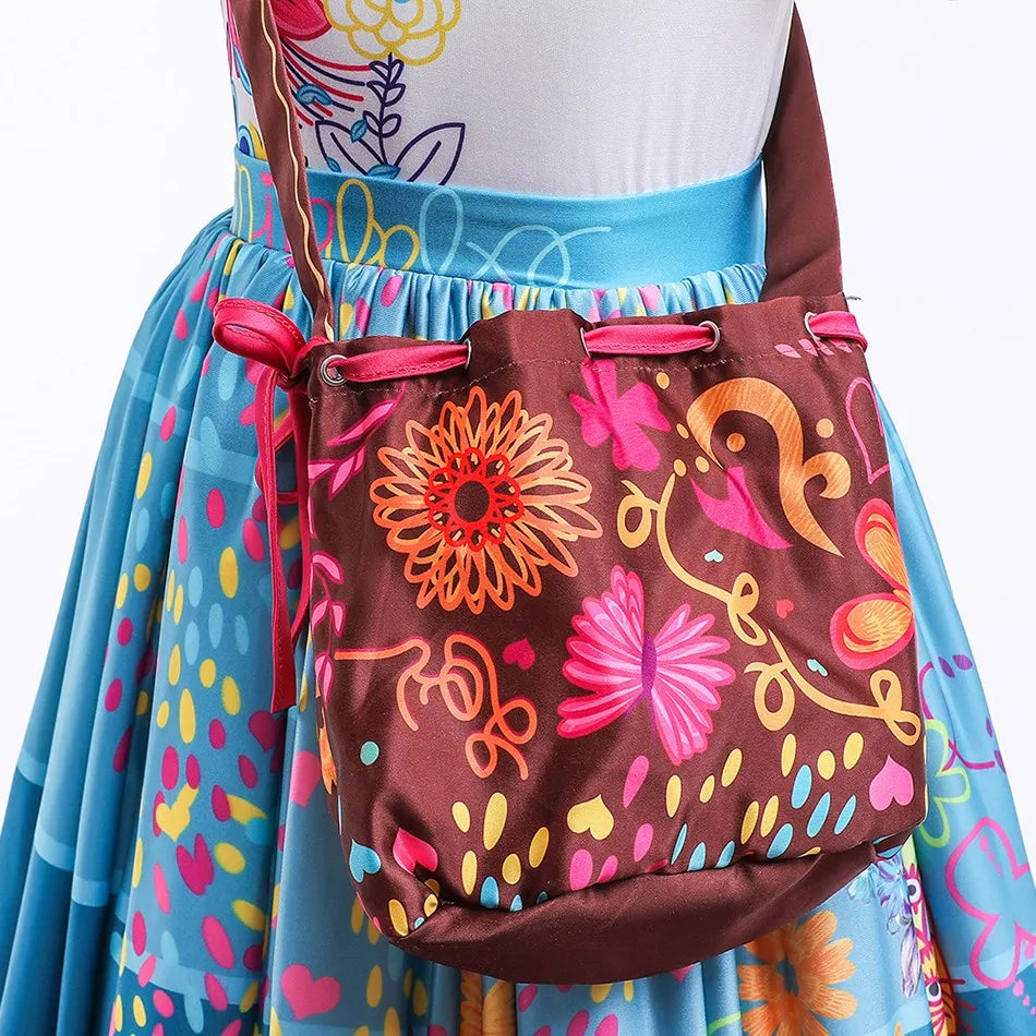 Ein Mädchen trägt ein blaues, farbenfrohes Kleid mit einer braunen Stofftasche am Oberteil.
