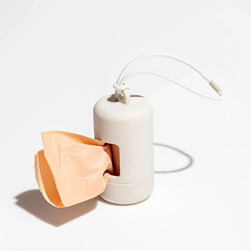 A beige portable dog poop bag dispenser with a white cord and an attached bag.