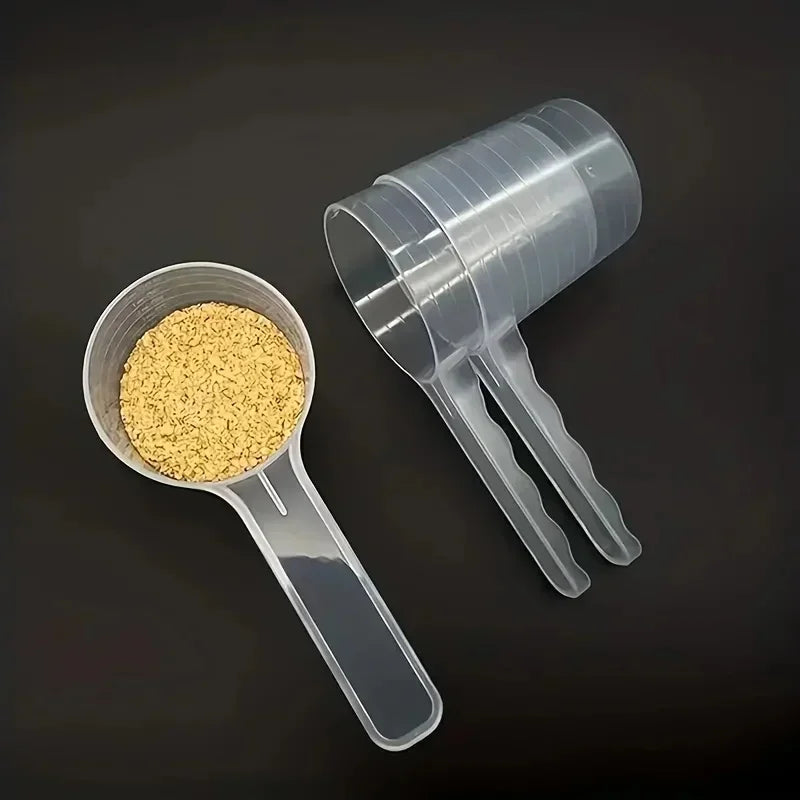 A transparent pet measuring spoon with a scale is shown next to a clear plastic container filled with yellow kibble.