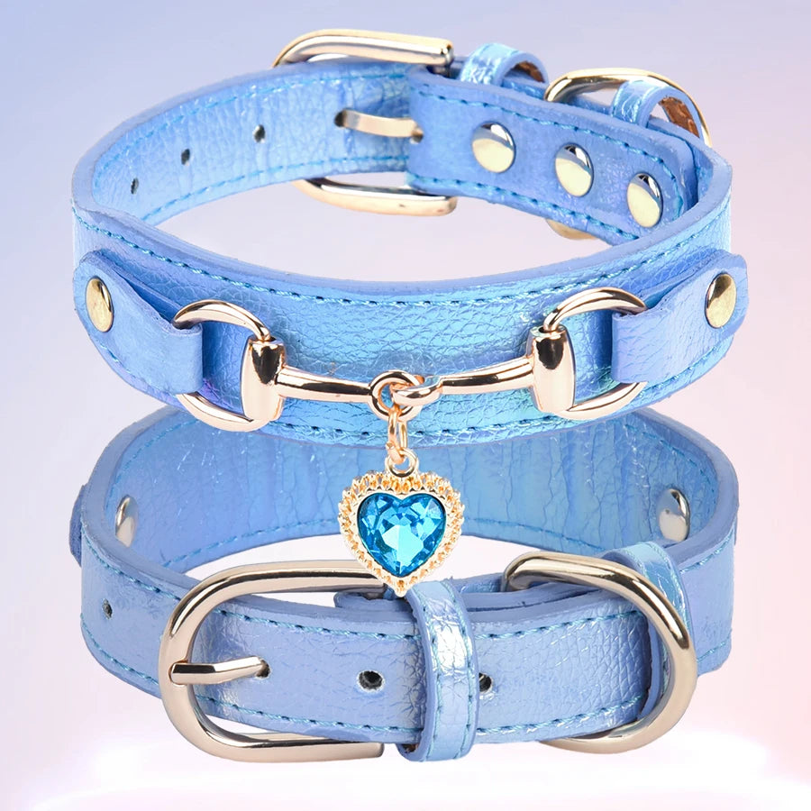 A light blue leather dog collar with a gold buckle and a heart-shaped rhinestone charm.