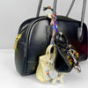Black leather handbag with a gold zipper and a colorful beaded puppy keychain charm