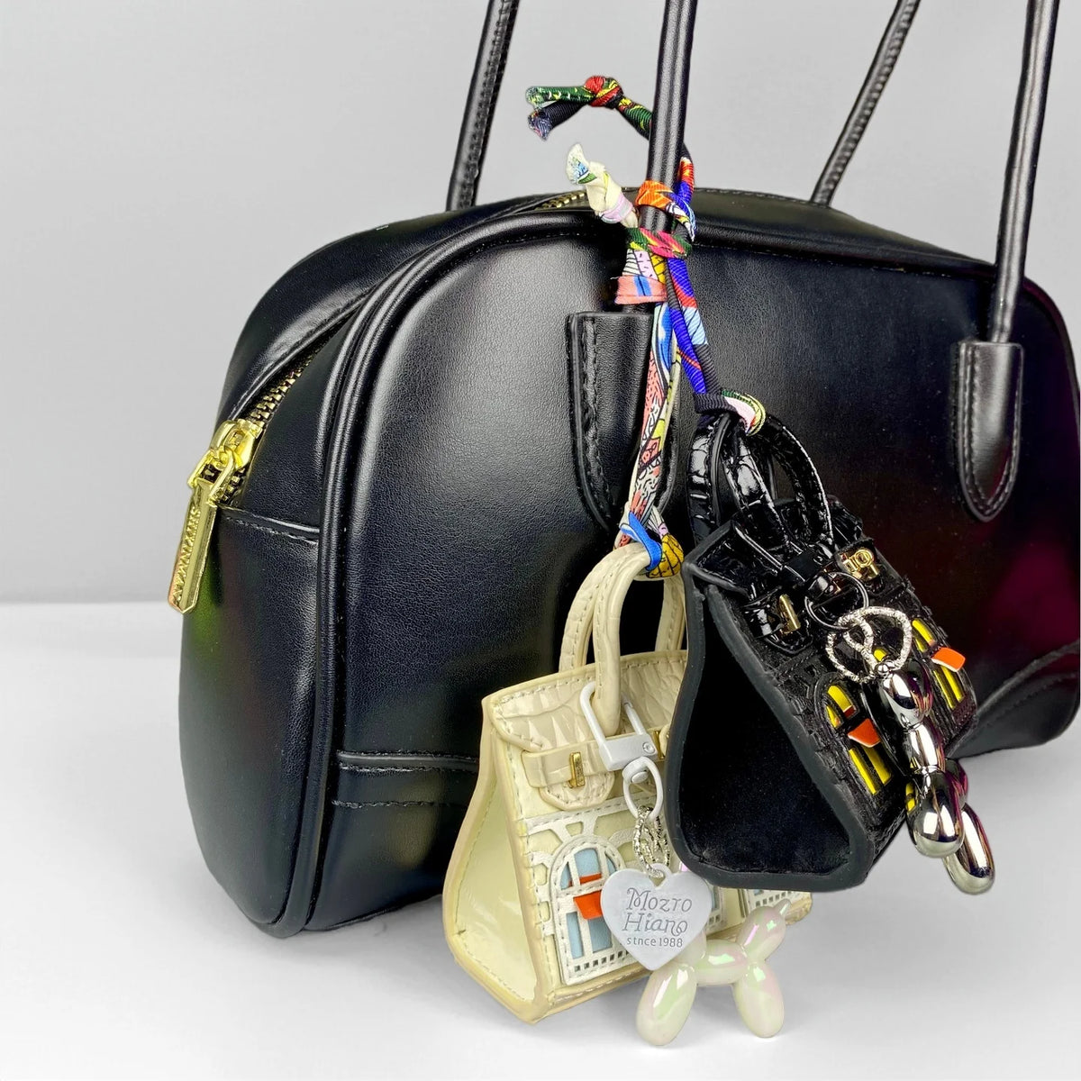 Black leather handbag with a gold zipper and a colorful beaded puppy keychain charm