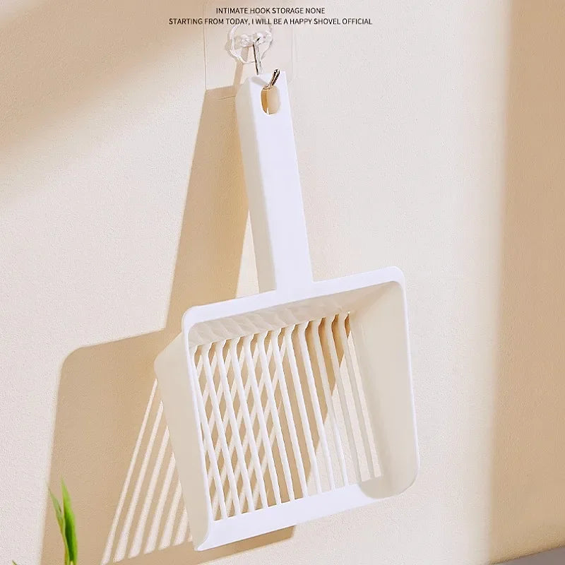 A white extra-large cat litter scoop with a hanging hook is displayed against a light wall.