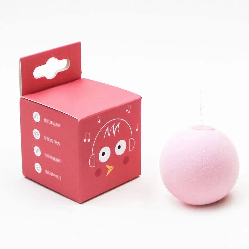 A pink cardboard box for an interactive cat sounding toy with catnip, next to the spherical toy.