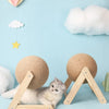 A fluffy gray kitten is resting on a wooden base with a sisal rope, surrounded by decorative clouds and heart shapes.