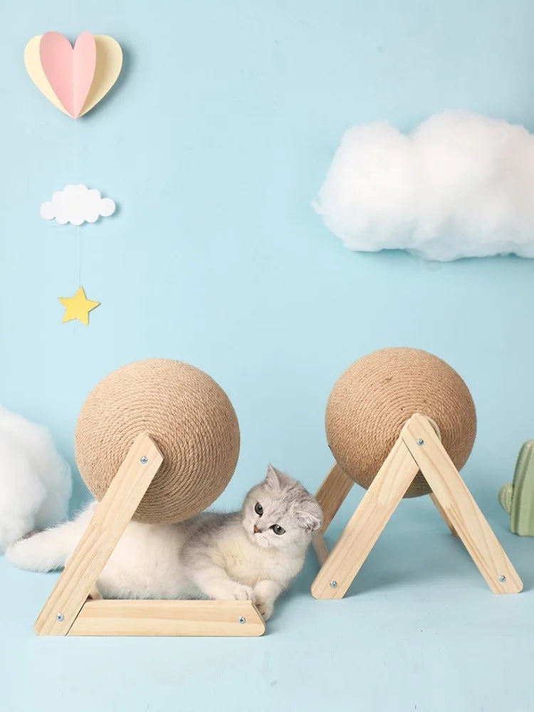 A fluffy gray kitten is resting on a wooden base with a sisal rope, surrounded by decorative clouds and heart shapes.