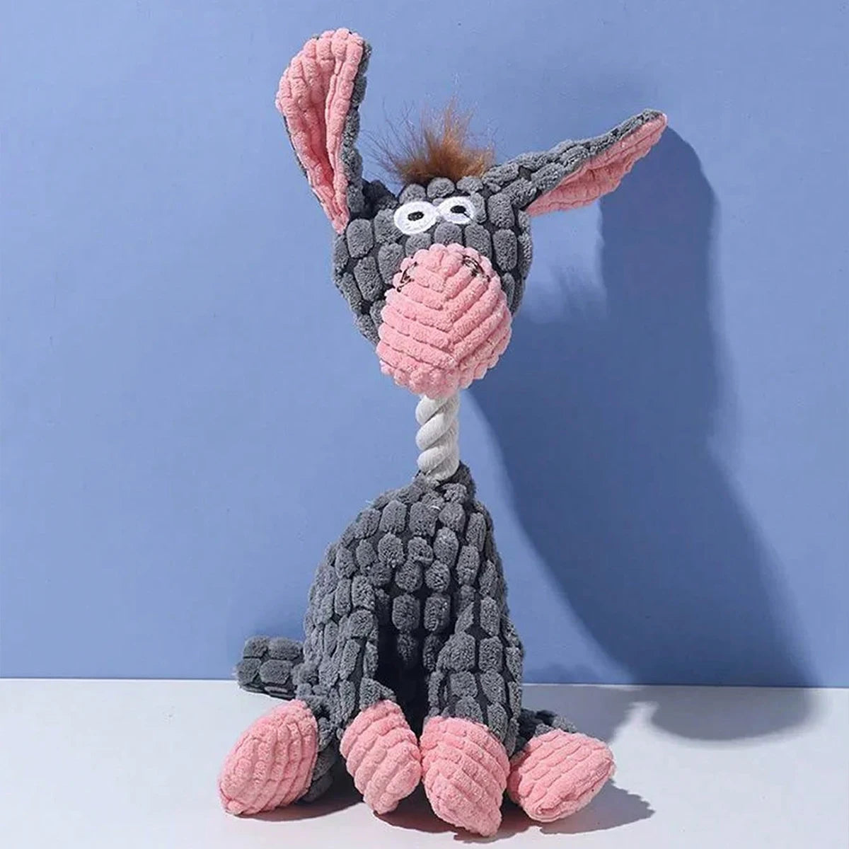 A gray and pink plush toy shaped like a donkey with long ears and a striped nose.